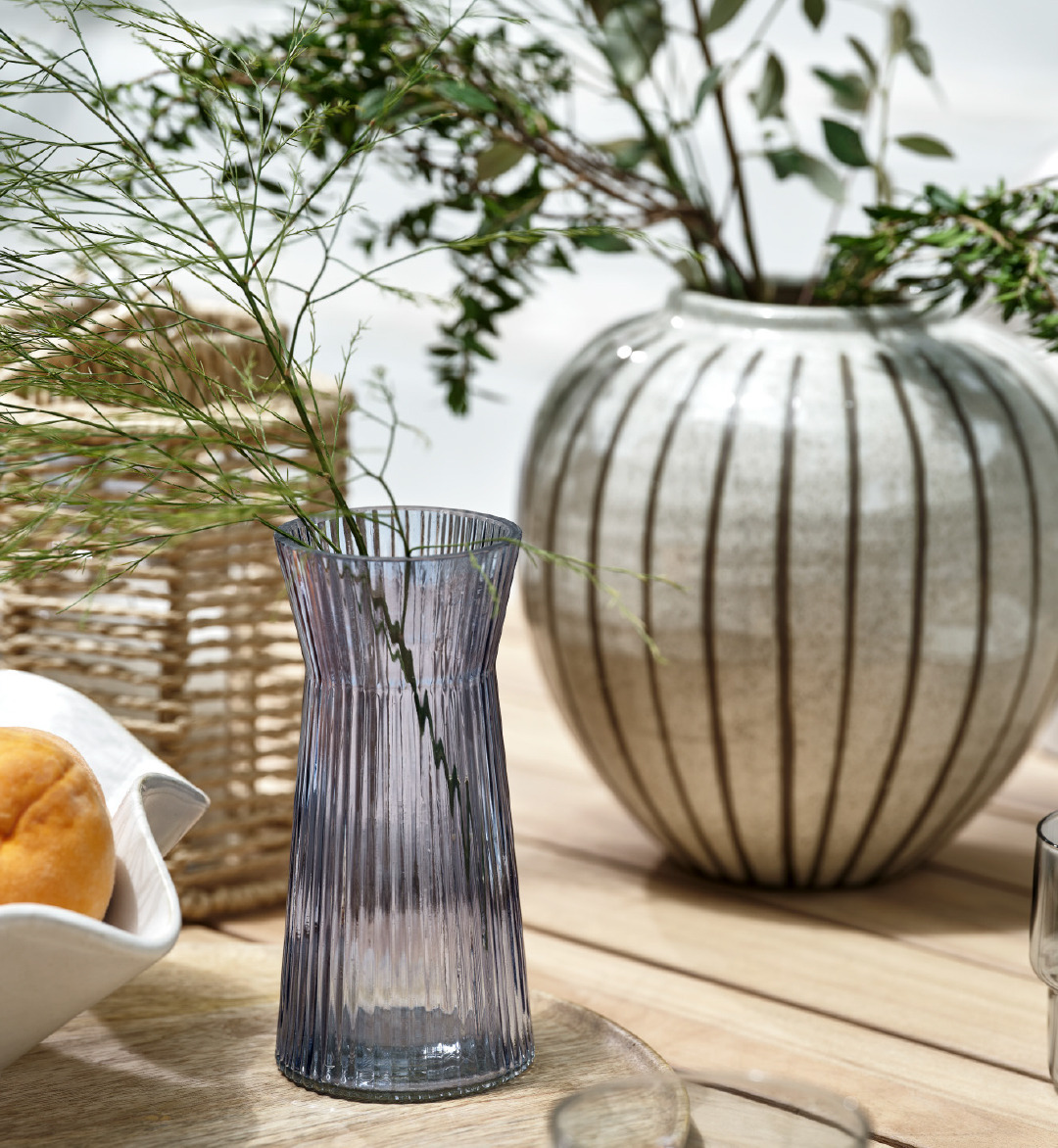 Скляна ваза HILBERT та керамічна ваза SOFUS на садовому столі - чудощві деталі, що додають атмосфери свіжості та скандинавського стилю вашому затишному майданчику.