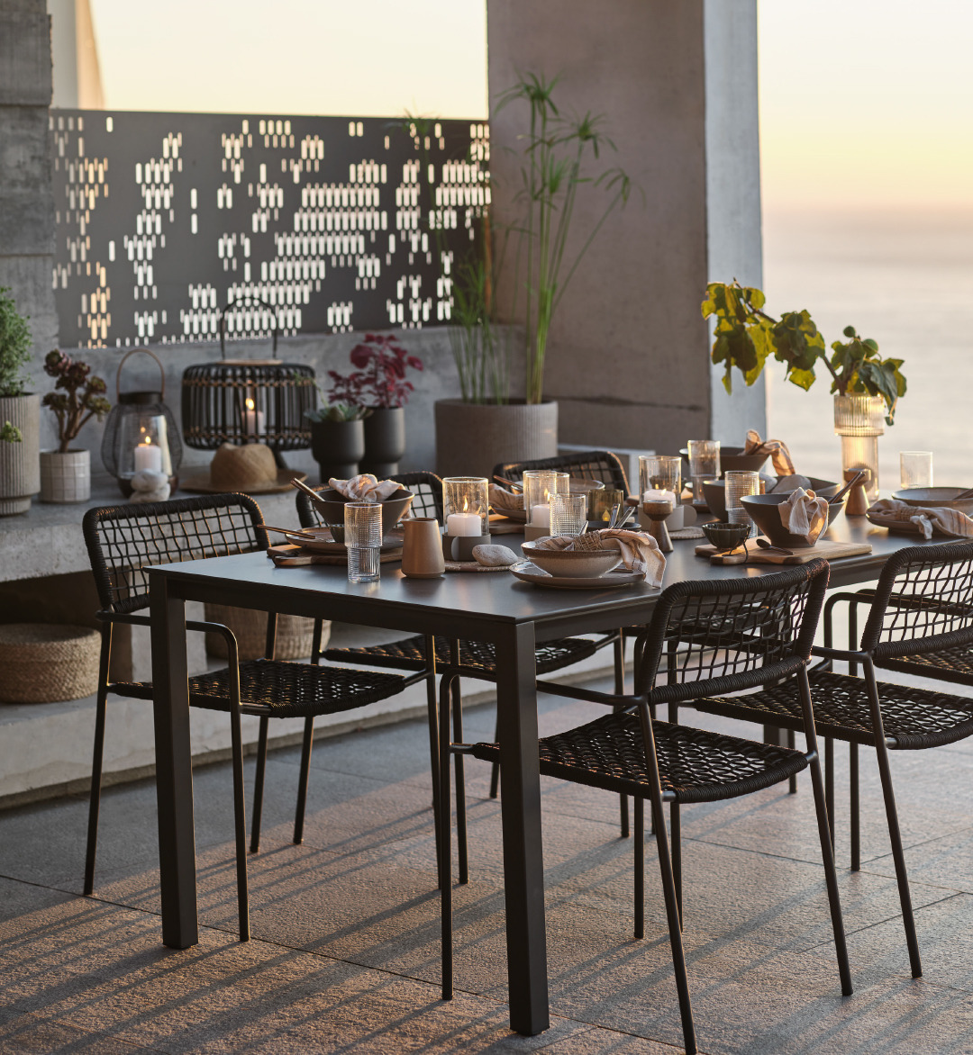 Чорний садовий стіл LANGET та садові стільці LABING створюють враження елегантності та затишку на терасі під час заходу сонця.